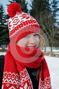 Beautiful blond girl in red cap and scarf.Traditional Â  Christmas decorative knitted pattern in Scandinavian style